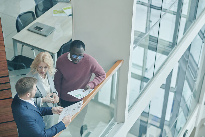 Three people talking in office balcony