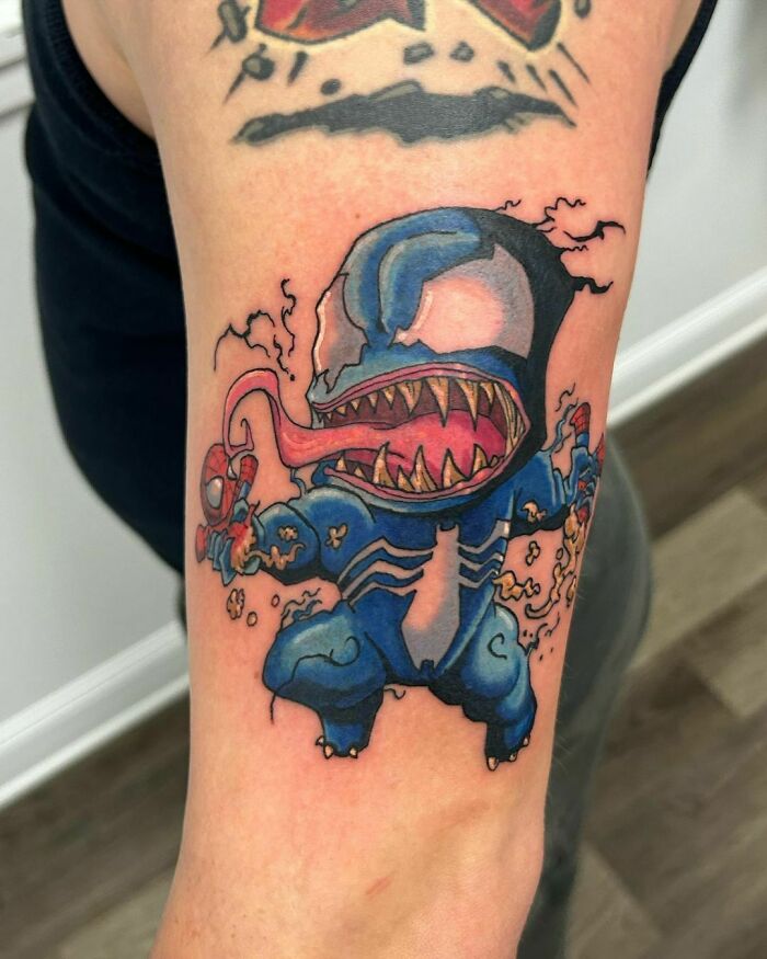 Cartoon-style Marvel tattoo of Venom on an arm, featuring vibrant colors and dynamic design.
