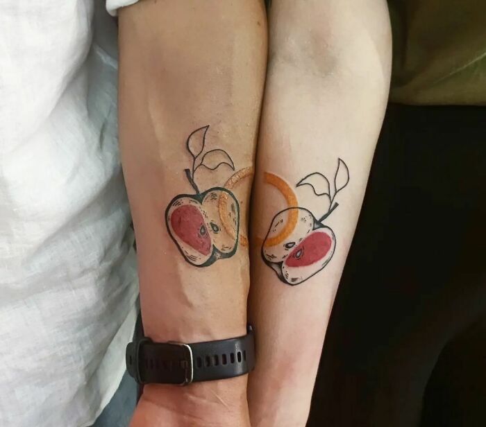 Matching tattoos of two apples on forearms, symbolizing connection between couples, siblings, and friends.