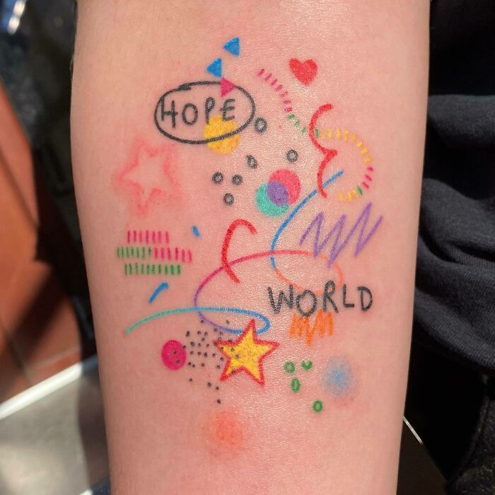 Colorful self-love tattoo with words "Hope" and "World" in vibrant shapes and patterns.
