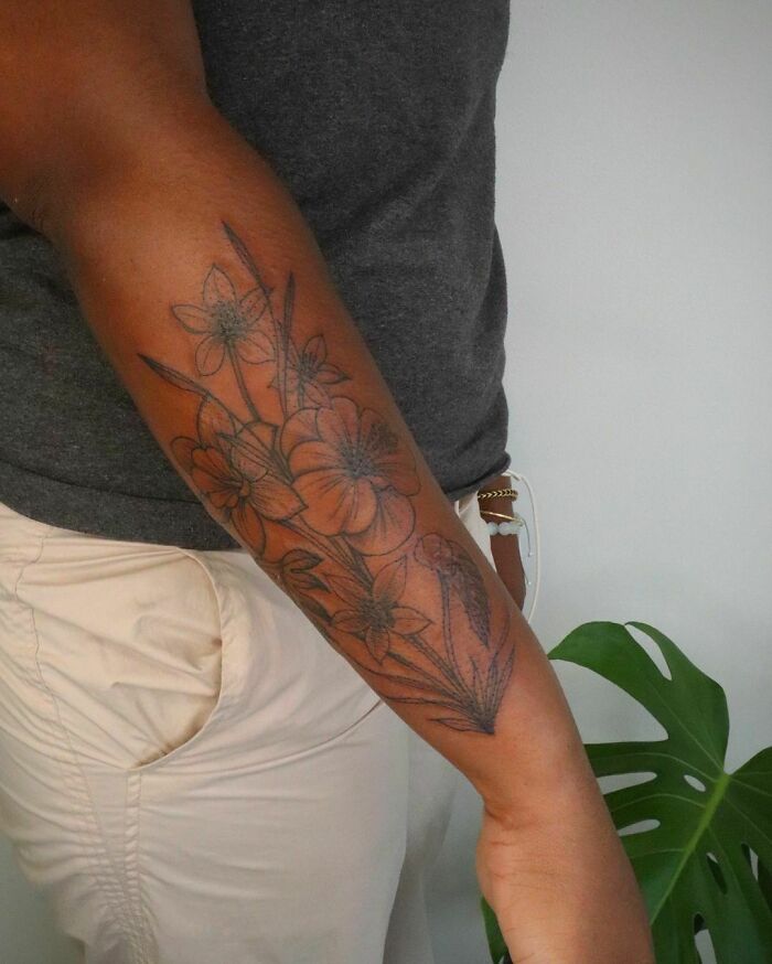 Floral tattoo on forearm radiating elegance and beauty, featuring detailed flower designs in black ink.