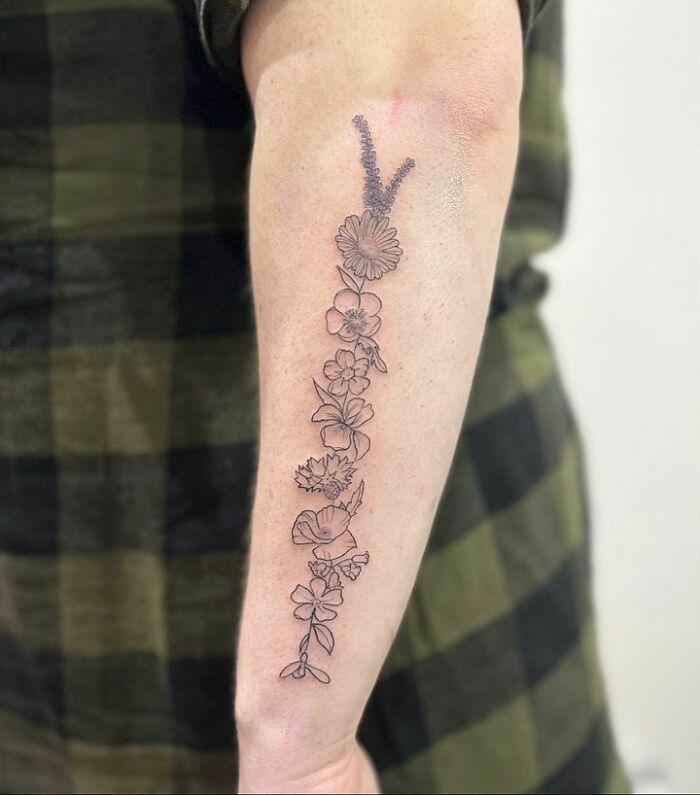 Arm adorned with delicate flower tattoos, creating a blossoming effect on the skin.