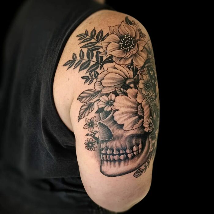 Elegant flower tattoo with a skull design on a person's upper arm.