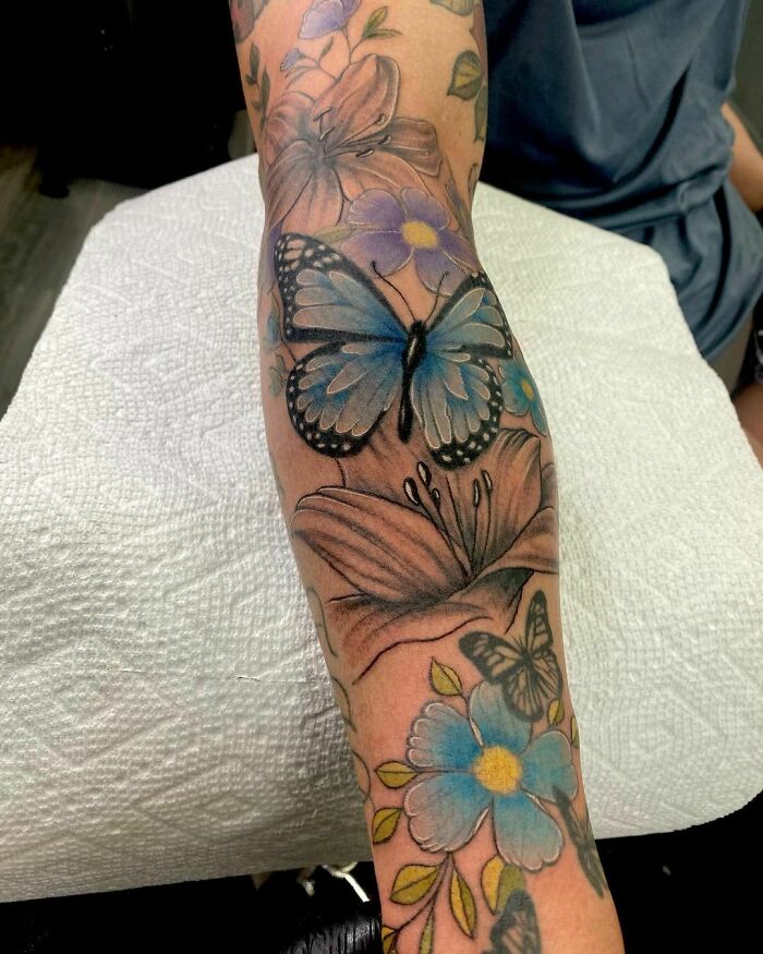 Blue butterfly and floral tattoo showcasing elegance and beauty on a person's arm.