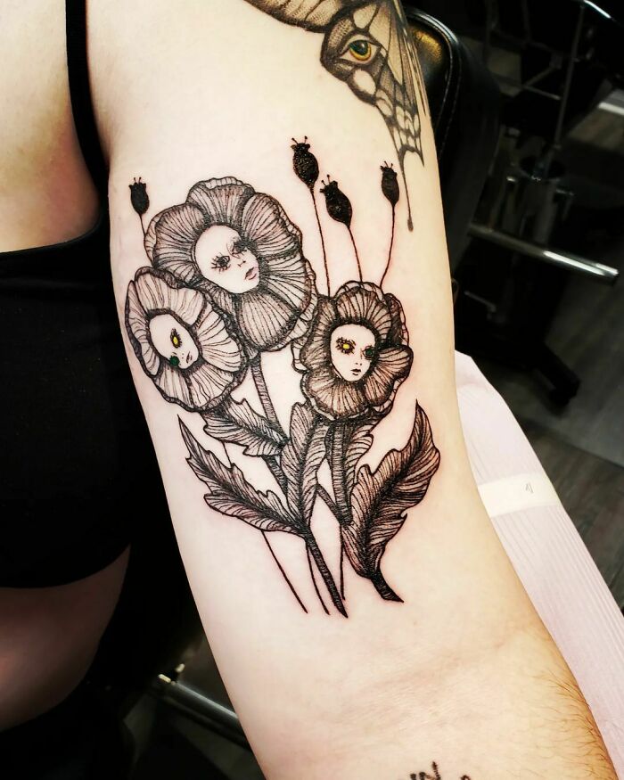 Flower tattoos with faces intricately drawn on arm, showcasing unique blossom design.