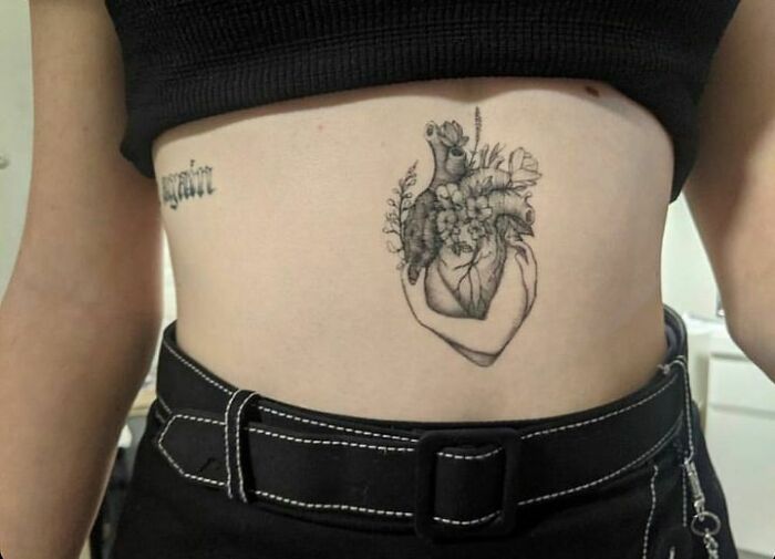 Floral heart self-love tattoo on a person's ribcage, symbolizing deep personal meaning and empowerment.