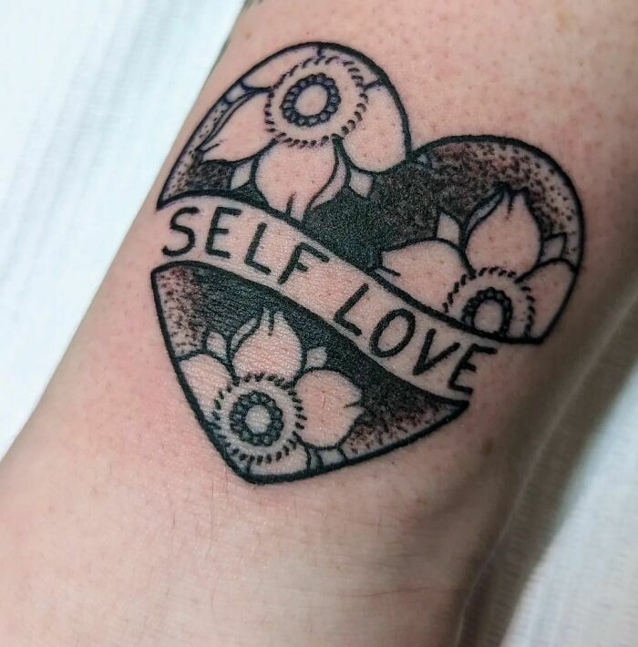 Self-love tattoo with heart and flower design, symbolizing empowerment.
