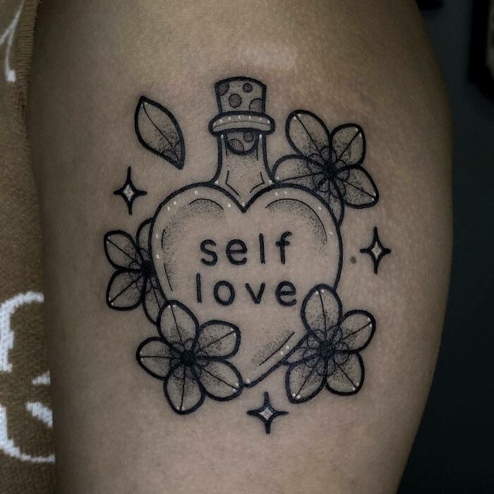 Heart-shaped bottle tattoo with "self love," surrounded by flowers and leaves.