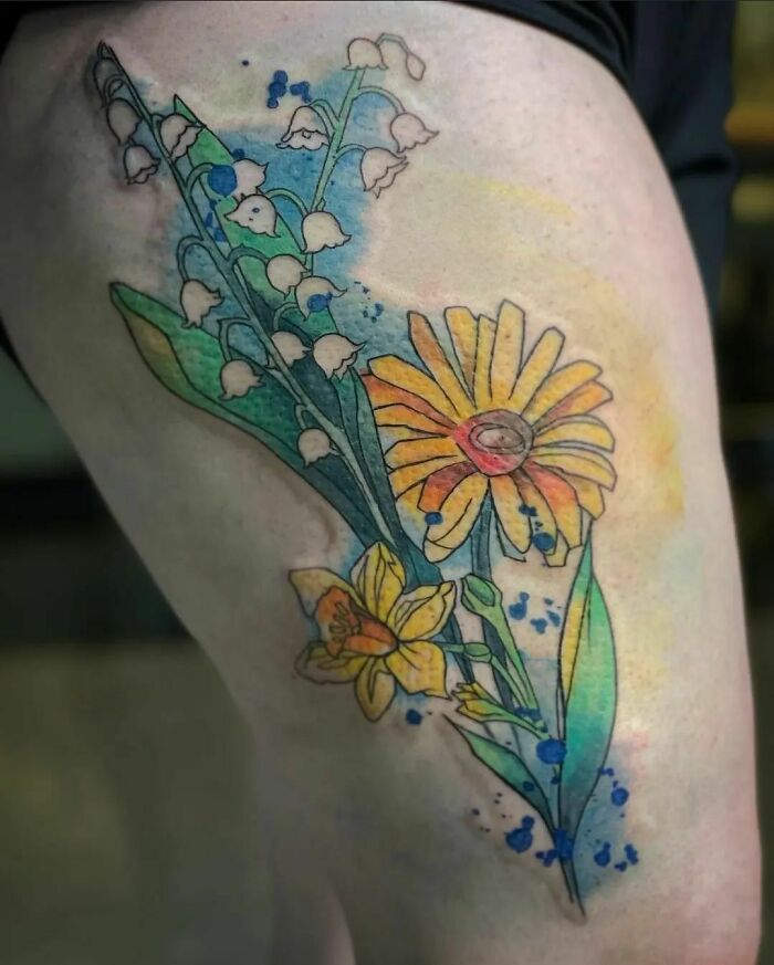 Colorful flower tattoo with daisies, lilies, and daffodils in a blossoming design on the skin.