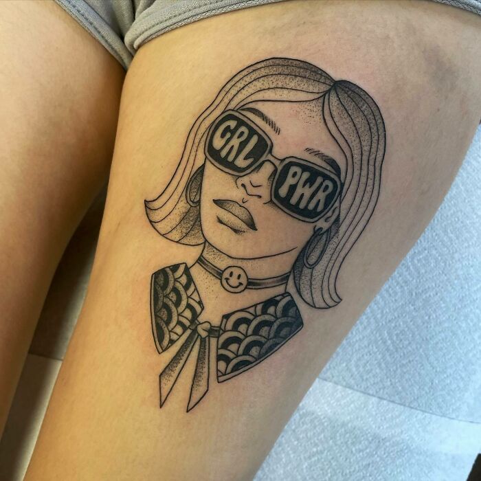 Self-love tattoo featuring a woman wearing "GRL PWR" sunglasses on a thigh.