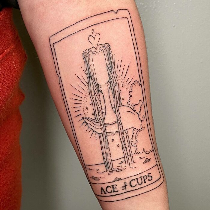 Ace of cups tattoo on forearm, featuring flowing water and celestial elements, symbolizing self-love and personal celebration.