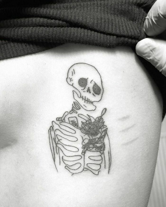 Sad skeleton tattoo on skin, representing self-love.