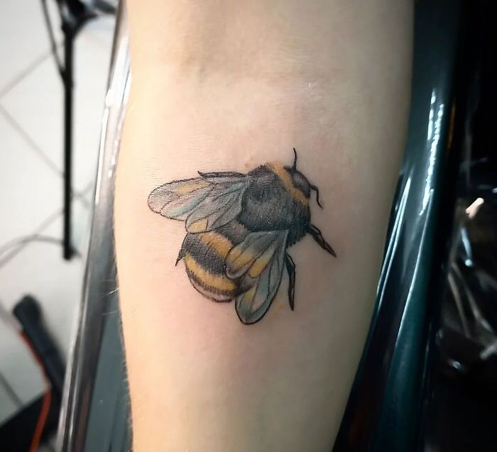 Realistic bee tattoo on forearm, showcasing simplicity and intricate design.