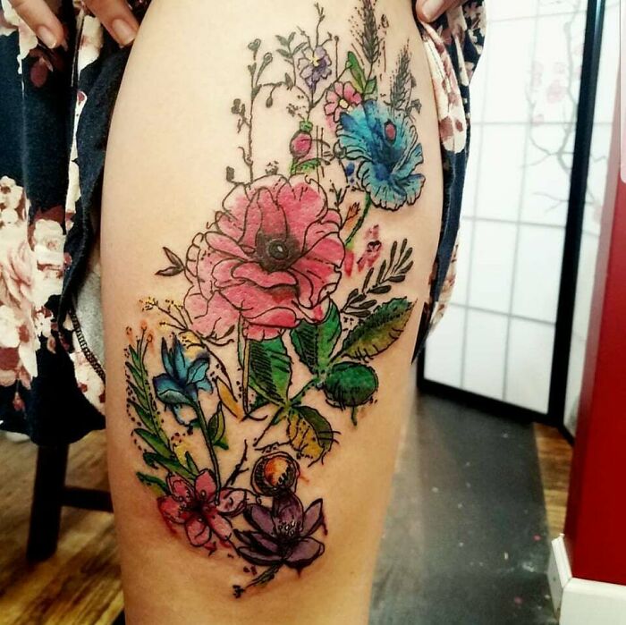 Colorful flower tattoos on skin featuring pink and blue blossoms with intricate details.
