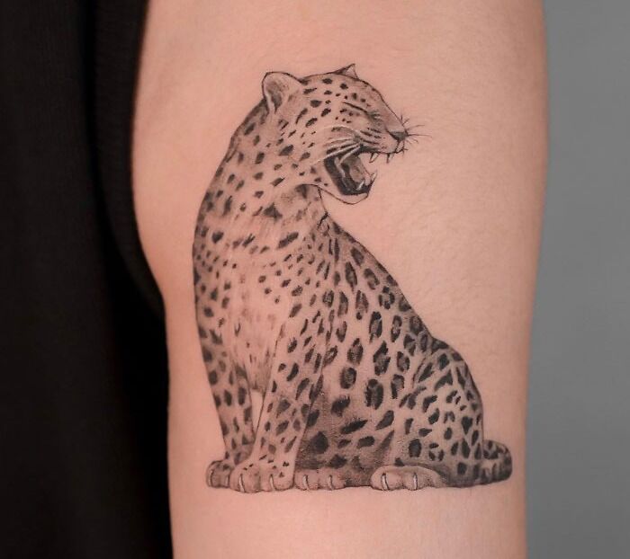 Realistic animal tattoo of a roaring leopard on arm, showcasing simplicity in design.