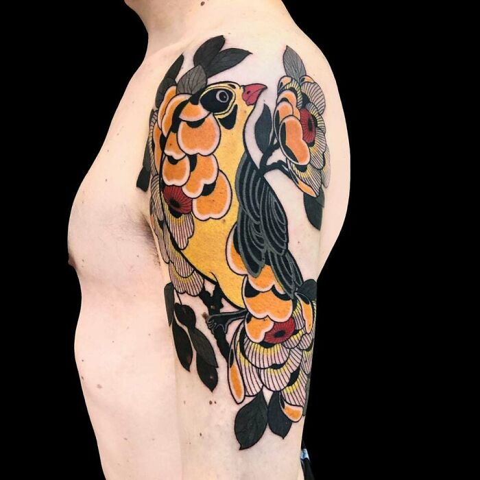 Floral tattoo with a bird design on a man's upper arm, showcasing elegance and beauty.