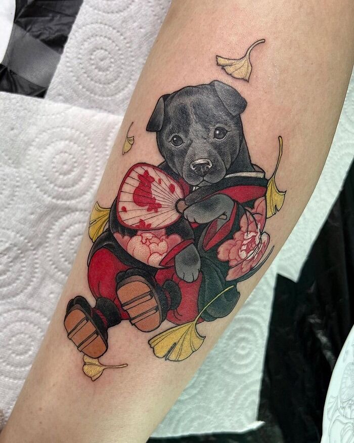 Realistic dog tattoo with detailed flowers and leaves on the arm, showcasing animal tattoo artistry.