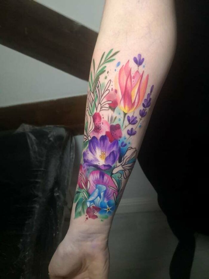 Colorful flower tattoo on forearm, featuring tulips and lavender, radiating elegance and beauty.