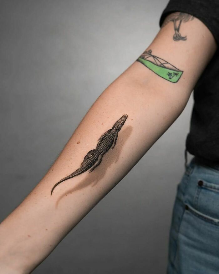 Realistic alligator tattoo on forearm, showcasing simple and detailed animal design.