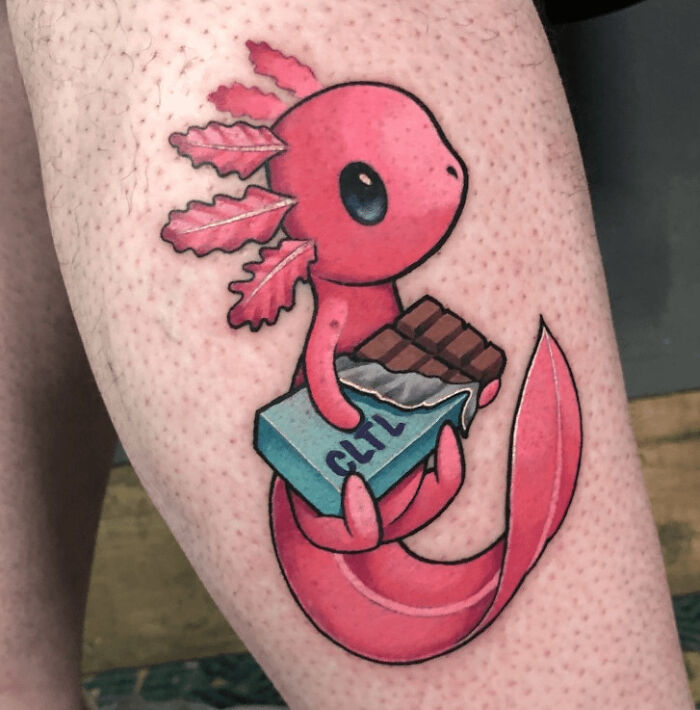 Simple, realistic animal tattoo of a pink axolotl holding a chocolate bar on someone's leg.