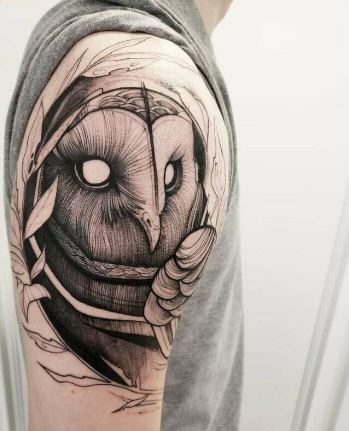 Owl tattoo with realistic details and simplicity on a person's upper arm.