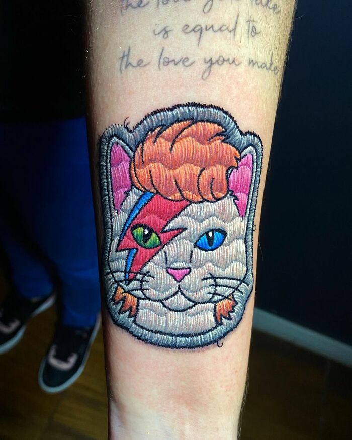 Cat tattoo resembling David Bowie with colorful zigzag, showcasing Eduardo Lozano's unique tattooing style.