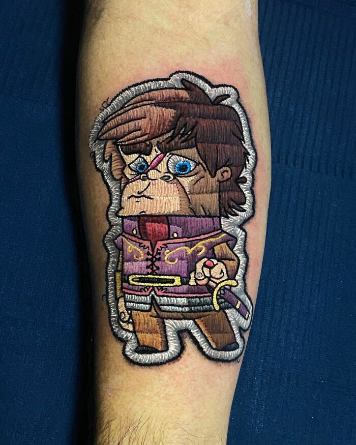 Tattoo by Eduardo Lozano featuring a cartoonish warrior with blue eyes and a sword, showcasing unique 3D effects.