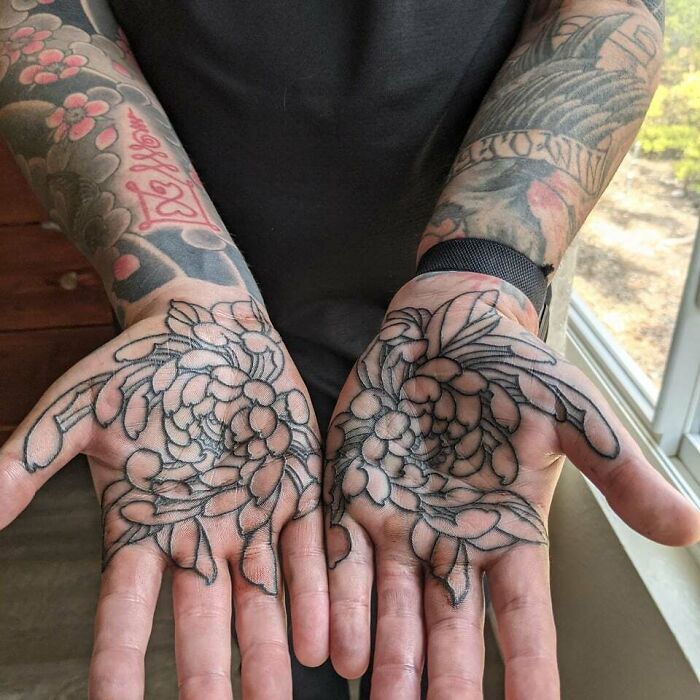 Floral tattoos on palms showcasing elegance and beauty in detailed black ink design.