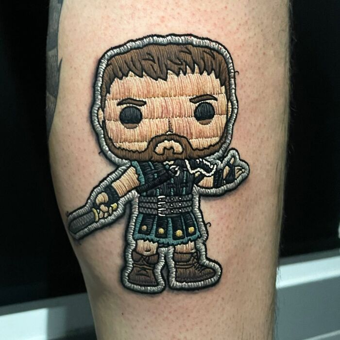 Embroidery-style tattoo by Eduardo Lozano, featuring a warrior character with intricate stitching effects.