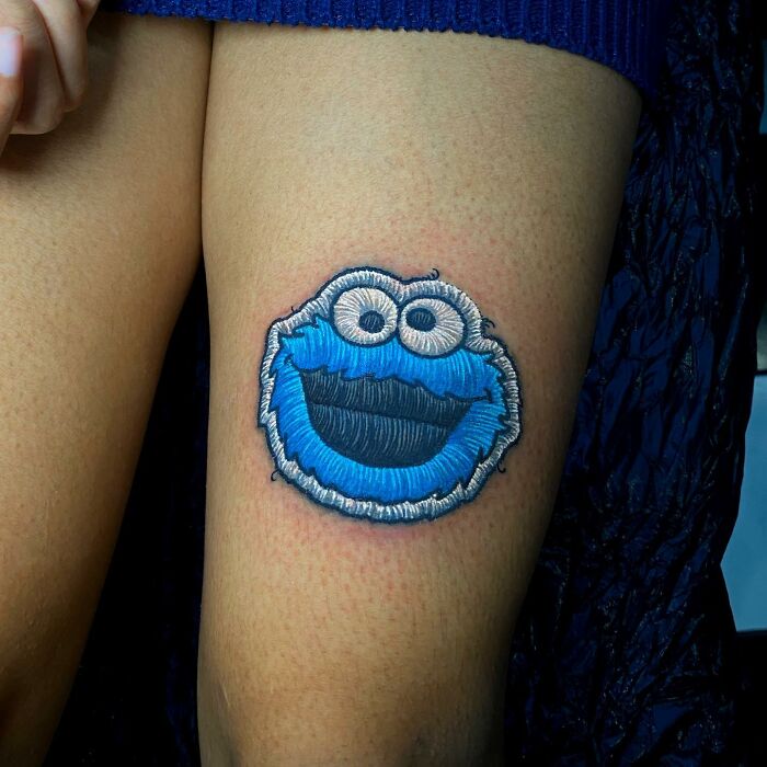 Tattoo of a blue character on a leg, showcasing Eduardo Lozano's innovative tattooing style.
