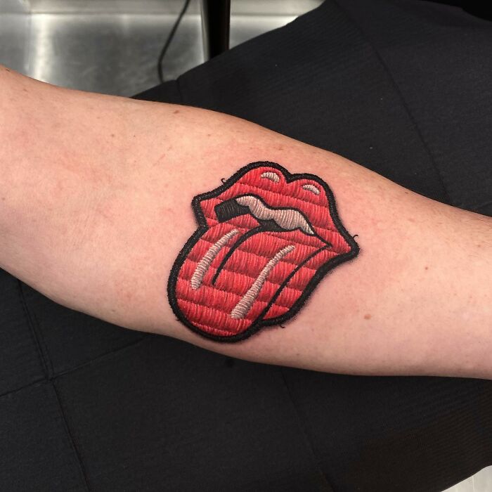 Tattoo of embroidered red lips with tongue, showcasing Eduardo Lozano's innovative dimension in tattooing.