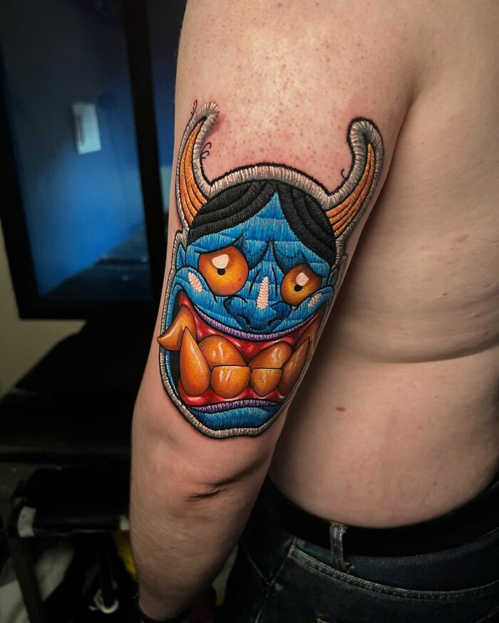 Colorful mask tattoo on an arm, showcasing Eduardo Lozano's innovative tattooing style.