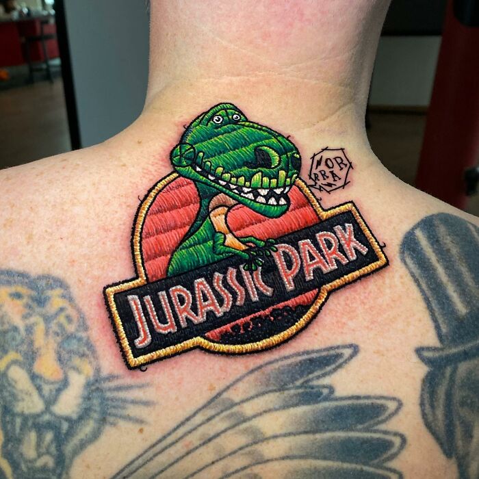 Tattoo by Eduardo Lozano featuring a vibrant Jurassic Park design on a person's upper back.