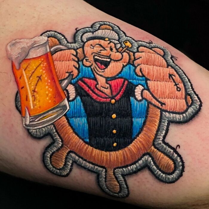 Tattoo of a cartoon sailor with a beer mug, showcasing Eduardo Lozano's unique embroidery-style technique.