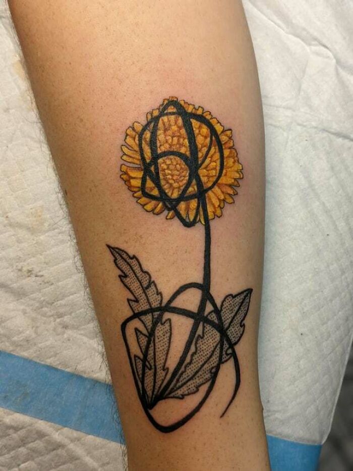 Yellow flower tattoo with abstract black lines, creating a blossoming effect on skin.