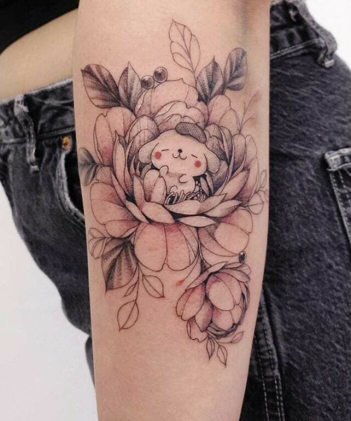 Floral tattoo with cartoon character, featuring blooming flowers and leaves on skin.