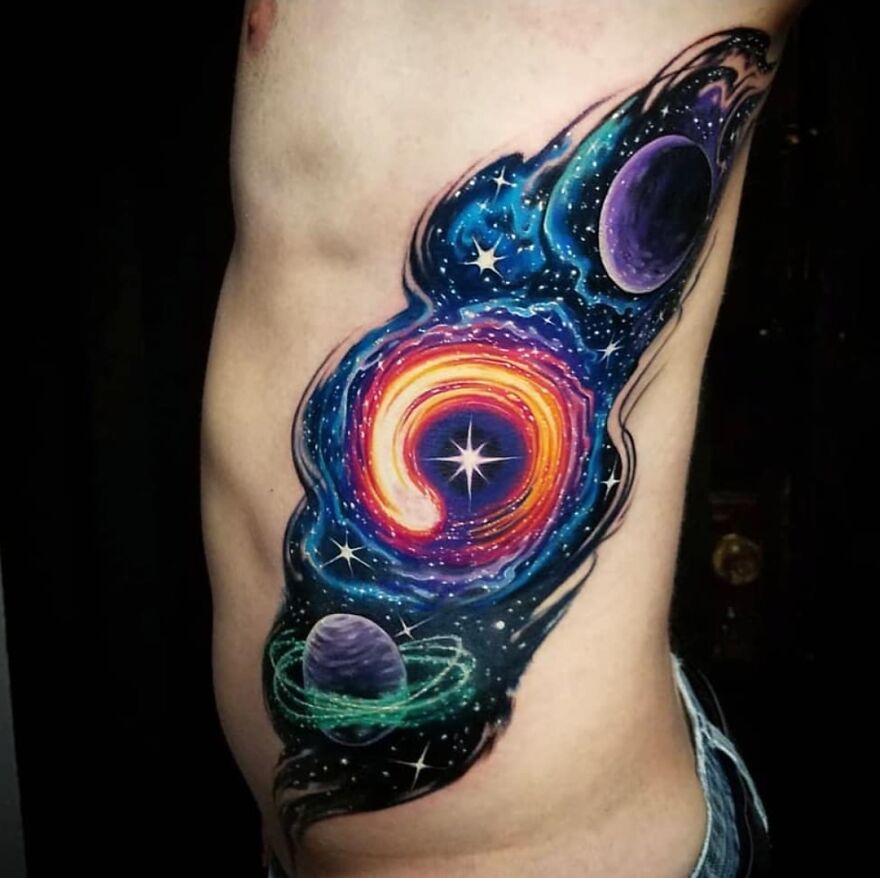 Space tattoo depicting a vibrant cosmic scene with planets and stars in vivid colors on a person's side.
