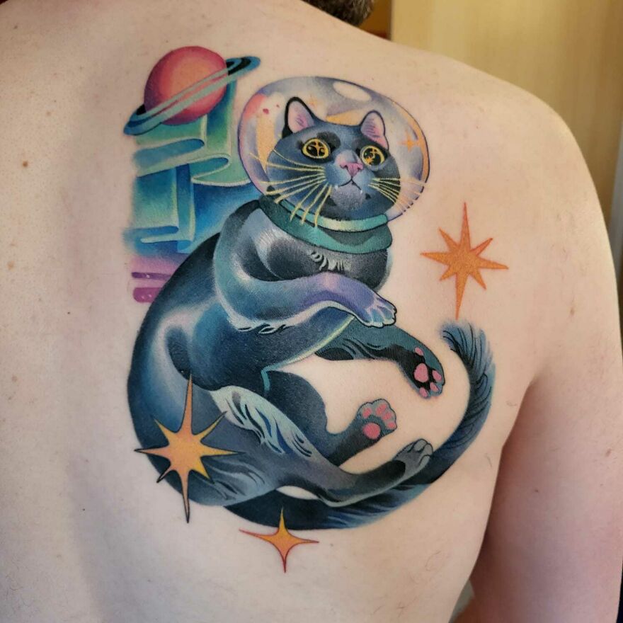Space tattoo of a cosmic cat with planets and stars on a person's back.