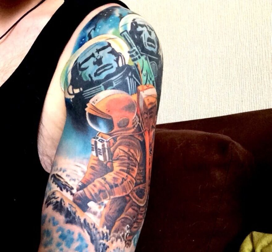 Space tattoo of astronauts and planets on an arm, showcasing colorful outer space themes.