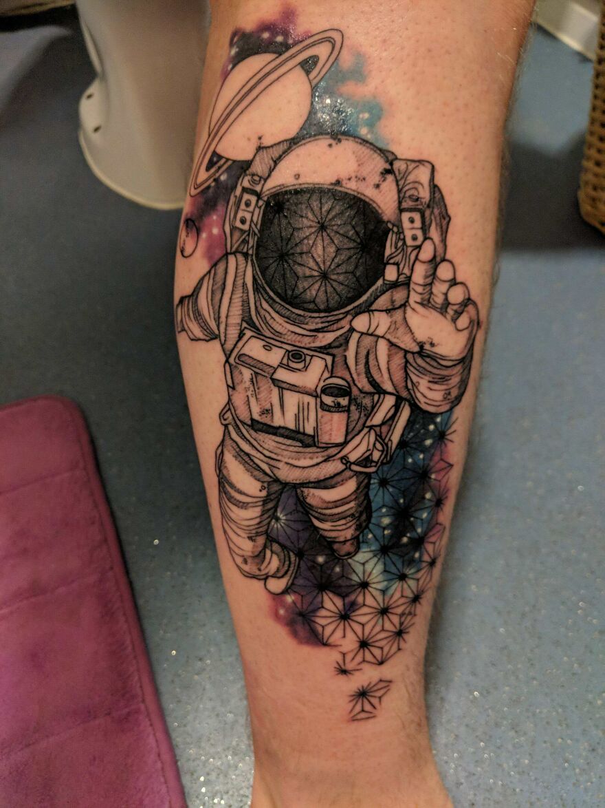 Space tattoo featuring an astronaut floating with a backdrop of stars and planets.