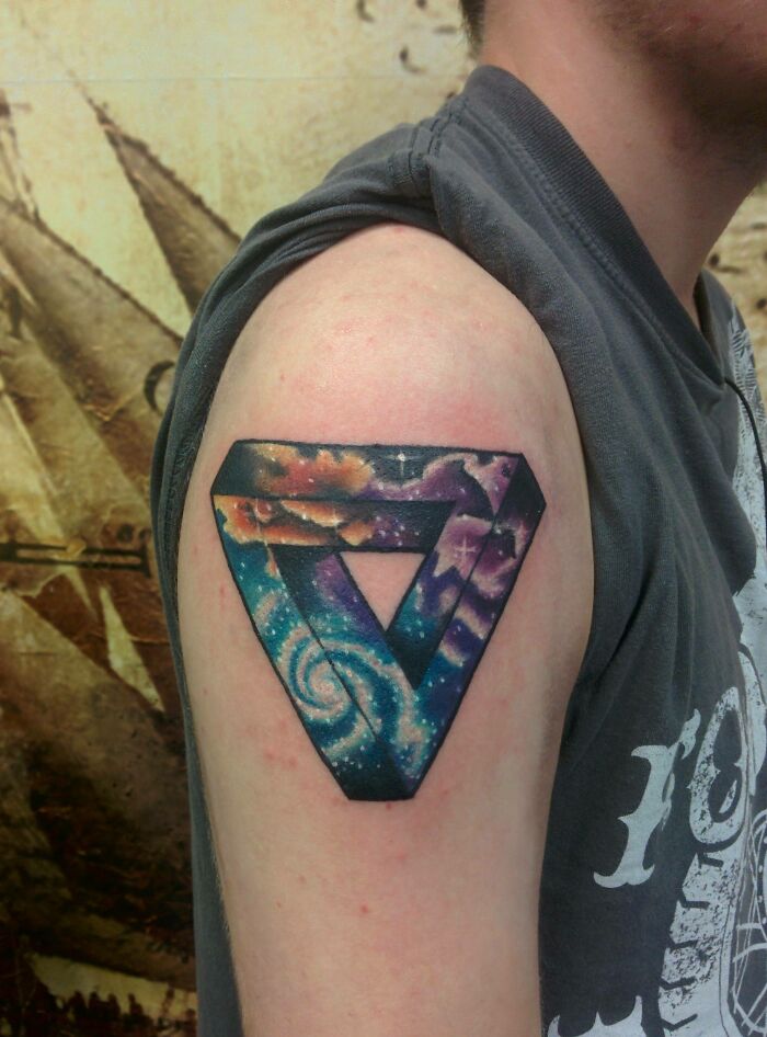 Space tattoo on upper arm with colorful galaxy design in an optical illusion pattern.
