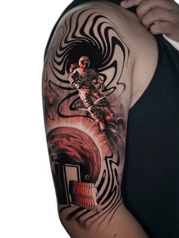 Space tattoo featuring an astronaut with a cosmic black hole design on an arm.