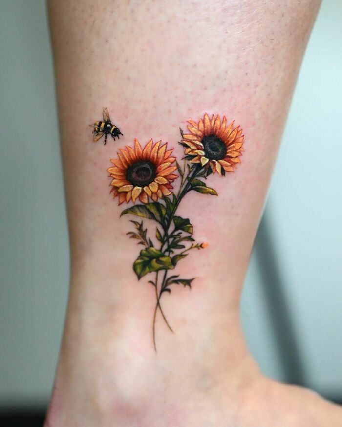 Sunflower tattoo with a bee, showcasing elegance and beauty on the skin.