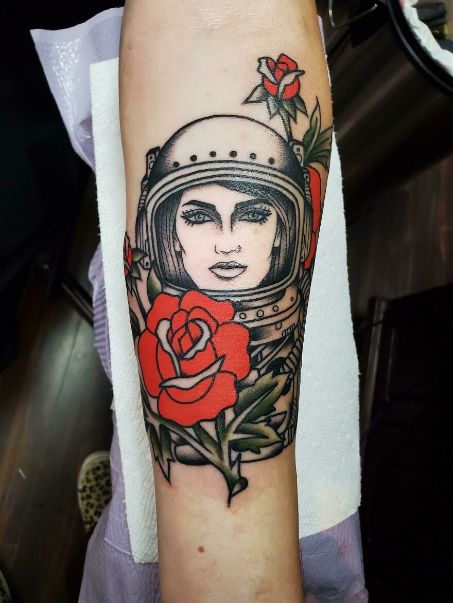 Astronaut tattoo with roses, featuring bold outlines and vibrant colors, showcasing outer space cool design.