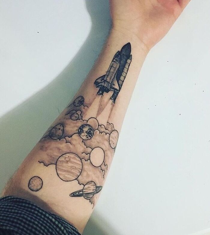 Space tattoo of a rocket launching through planets and clouds on an arm.