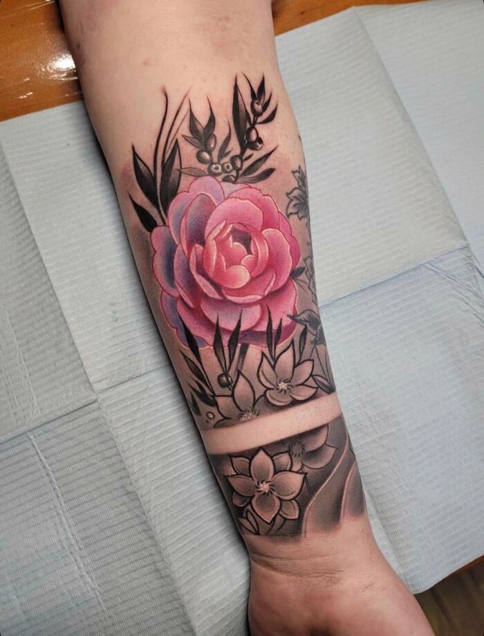 Colorful flower tattoo with a blooming rose design on forearm.