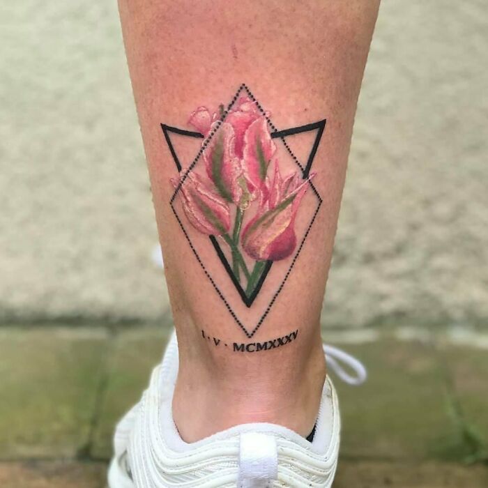 Geometric flower tattoo on leg with Roman numerals, blending artful blossom with skin.