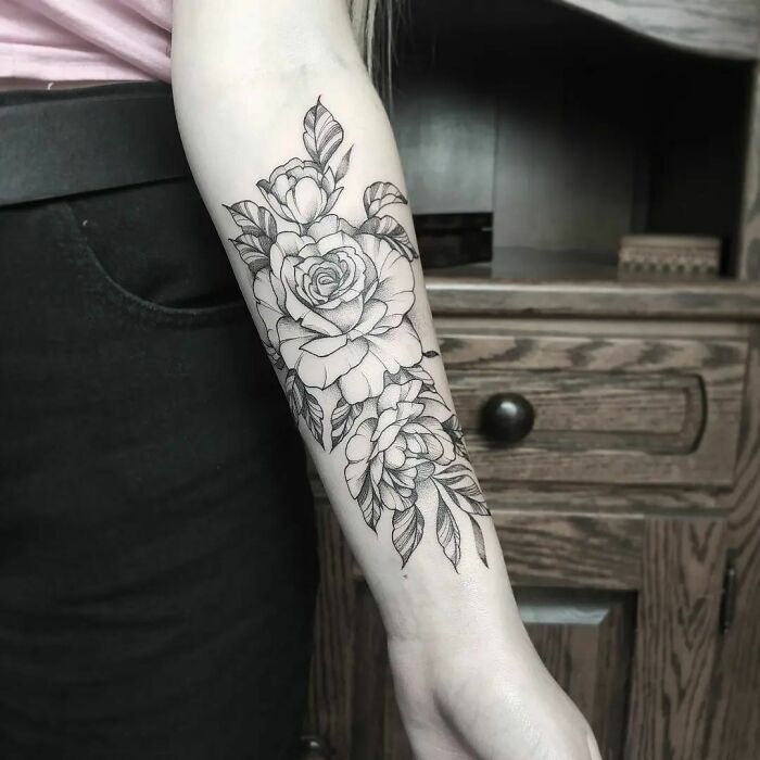 Floral tattoo design on forearm, showcasing intricate blooming flowers in black ink.