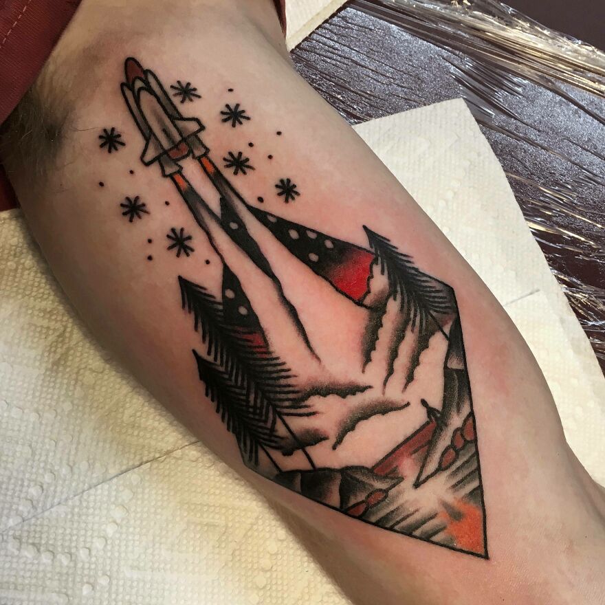 Outer space tattoo featuring a rocket launch with stars and trees, blending nature and space themes.