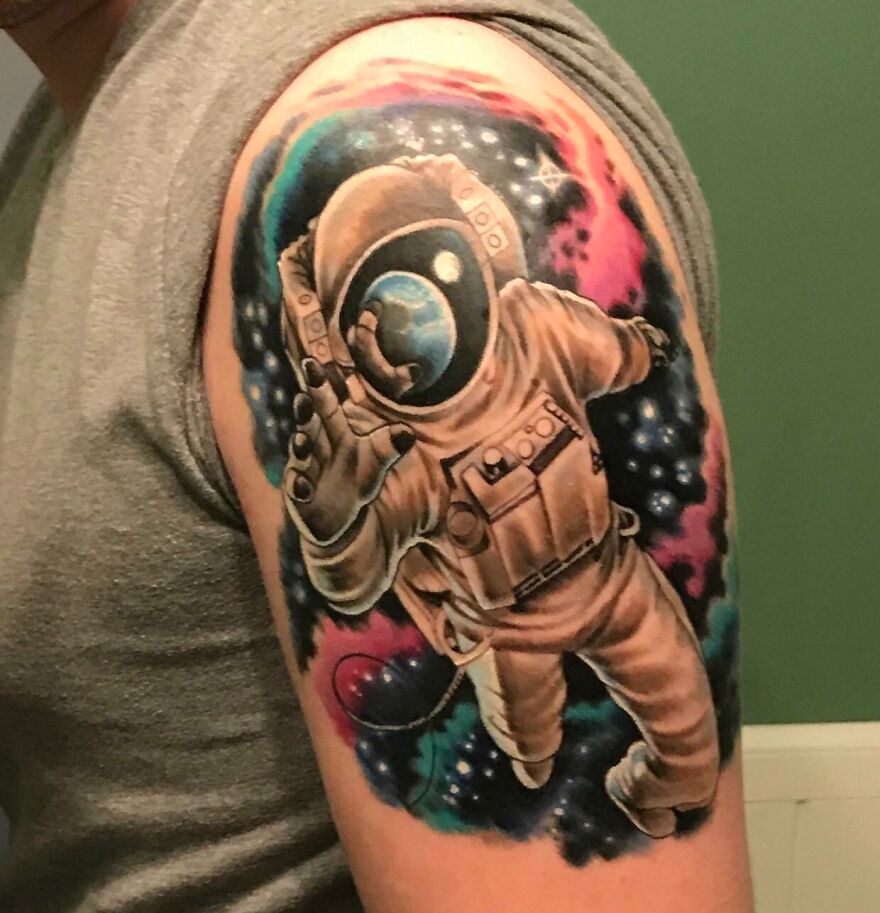 Astronaut tattoo design for space and astrology enthusiasts, featuring vibrant cosmic colors on an upper arm.